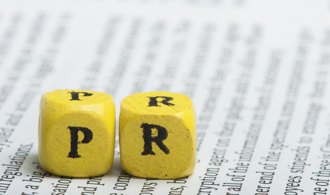 Word PR.Wooden cubes on newspaper. Close up studio shot